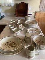 Set of Royal Doulton floral dishware arranged on countertop with wooden towel rack in background.