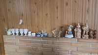 Photo showing all items arranged on a mantel including milk glass mugs, small ceramic and glass items, star shaped glass dish, small figurine with umbrella, and several wooden carved figurines.