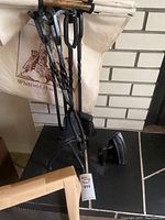 Fireplace tools set with twisted iron handles and different tool heads hanging together.