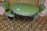 Full view of round folding metal card table with two matching folding chairs