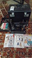 Full lot showing sewing machine, carrying case, box of notions, three patterns