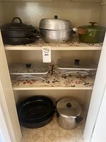 Photo of kitchen shelving with various pots and serving trays including cast iron and aluminum items