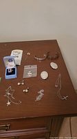 Full overview of various sterling silver jewelry items on table including bracelets, rings, necklaces, earrings, and pins.