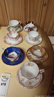 Six assorted tea cups and saucers arranged on table
