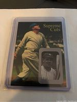 Front view of the Babe Ruth Supreme Cuts facsimile autograph trading card in a plastic sleeve showing Babe Ruth batting image and inset photo.