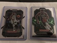 Front view of two Giannis Antetokounmpo Monopoly Prizm NBA cards showing player in Milwaukee Bucks uniform during a game.