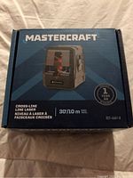 Front view of MasterCraft Cross-Line Laser Level box showing product image, brand, model, range, and 1 year warranty information.