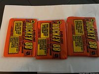 Three unopened O-Pee-Chee 1988 Hockey sticker packs, orange packaging with yellow and black text.