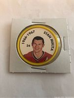 Front of hockey coin showing Stan Mikita in color with years 1966-1967 and number 24, encased in cardboard holder.