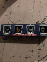 Photo of the four shot glasses in their original blue box, showing various Toronto Maple Leafs logos in blue and white.