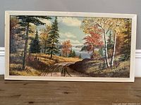 Full frontal view of the oil on board painting showing autumn landscape with lake and distant hills, framed in a white simple frame.