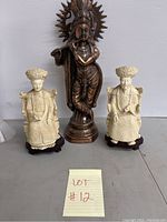 Overall view of the three Asian statues including bronze Krishna and two cream Chinese figures on stands