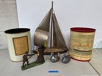 Full display of the lot including metal sailboat, trash bins, cast iron figurine and metal ducks