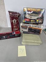 Lot of boxed inventory items including glass chilled pitcher, Big Mouth Billy Bass singing fish toy, storage cabinet box, cordless screwdrivers and sheets.