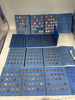 Four blue Whitman coin folders partially filled, arranged on white surface