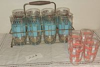 Full set showing 8 turquoise and gold glasses in metal caddy and 4 coral juice glasses outside
