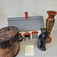 Overview of all items in the lot showing painted wood house, wood box, black cat figurine, and decorative vase