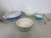 Image showing a blue chip and dip bowl with clear glass lid on a wire stand, white bowl with gold floral design, turquoise bowl, and a smaller turquoise chip and dip bowl with metal tongs.