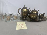 Full view of the brass tea set with tray alongside four square highball glasses, showing the entire lot.