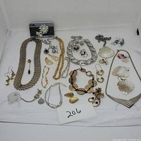 Overall view of the jewelry lot including various necklaces, earrings, bracelets and pins displayed on a white backdrop.