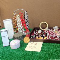 Overview of lot showing perfumes, trinket box, colorful beaded necklaces on metal stand, assorted jewelry on wooden tray