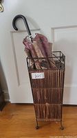 Full view of bamboo and metal umbrella holder with a vintage umbrella inside showing the overall shape and style