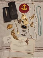 Full view of vintage jewelry lot including brooches, necklaces, earrings, ring, and Danbury Mint heart pendant with certificate