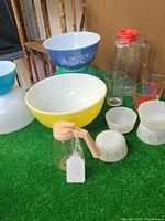 Lot of vintage bowls, pitchers, and glasses on green surface with wood background