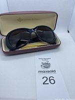 Blue oversized Camrose & Kross sunglasses inside branded cream interior maroon hard case.