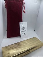 Gold textured clutch purse with red velvet pouch behind it, displayed in lightbox