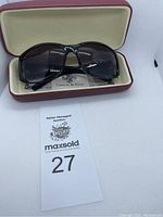 Black oversized replica sunglasses in red hard case with cream interior and Camrose & Kross branding