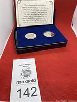 Set of two commemorative coins in blue velvet case along with an explanatory card and auction lot label
