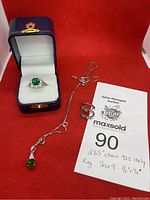 Silver jewelry set displayed on red fabric background with auction tag showing chain length and ring size details.