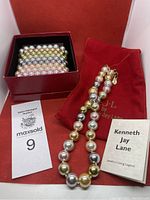 Overview of simulated pearl necklace, ten simulated pearl bracelets in a red box, KJL branded pouch and informational booklet.