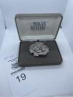 Brooch in original Nolan Miller box with MaxSold auction tag visible.