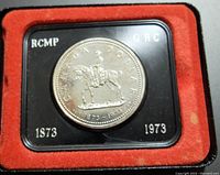 Silver Canadian $1 RCMP commemorative specimen coin displayed in original black holder with red velvet interior inside hinged case.