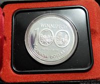 Close-up of the 1974 Winnipeg 100th Anniversary silver Canadian dollar coin in black plastic display mount, showing detailed coin face with 'WINNIPEG 1874-1974 CANADA DOLLAR' inscriptions.