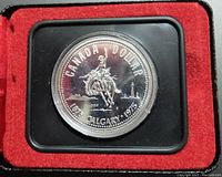 Close-up of the 1975 Canada silver dollar commemorative coin inside a black frame with red velvet cushioning.