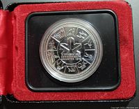 Close-up of silver coin showing zodiac signs and central maple leaf with text.