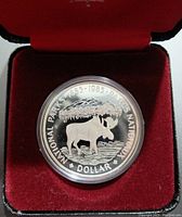 Close-up of the front face of the silver coin inside its protective capsule and red velvet box.