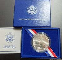 United States Liberty Coin presentation blue box with sealed silver dollar coin in protective capsule along with certificate card.