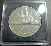Reverse side of the 1987 Canadian silver commemorative dollar coin showing sailing ship and inscriptions.