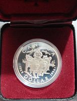 Obverse side of the 1994 Canadian silver $1 proof coin showing commemorative design depicting figures on horses dated 1969-1994, placed in a red velvet lined case.