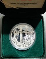 Close-up of the silver commemorative coin in a sealed capsule inside a green velvet presentation box showing detailed engraving of a royal figure and carriage with 'Canada Dollar' inscription.