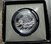 Close-up photo of the 2003 Canadian commemorative silver dollar coin sealed in a black plastic capsule within a box.