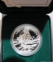 Close-up of the commemorative silver coin featuring a fox running in front of a mining headframe with 'Canada Dollar 1903-2003' inscription.
