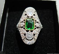 Front view showing the detailed filigree design, green rectangular gemstone, and two clear round accent stones set in sterling silver.