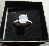 Front view of 925 silver gemstone fashion ring in black box showing cushion-cut clear stone and sparkle on band.