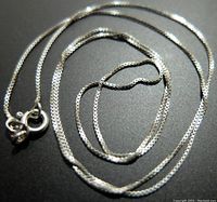 Close-up photo of the silver necklace showing details of the chain and clasp.
