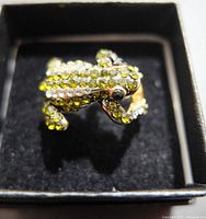 Front view of the ring showing the frog design heavily decorated in green and clear rhinestones.